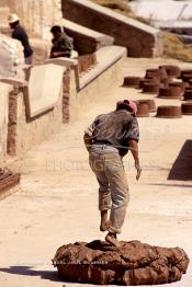 Image du Maroc Professionnelle de  Un ouvrier pétrit l’argile imprégnée d’eau dans les ateliers de la Colline des Potiers à Safi, Vendredi 29 Août 1997. (Photo / Abdeljalil Bounhar)